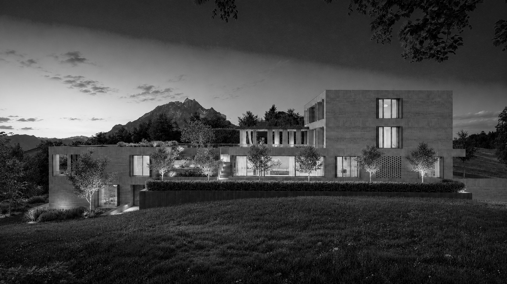 Villa Anemoi in der Abenddämmerung mit warm beleuchteten Fenstern, dahinter der Pilatus