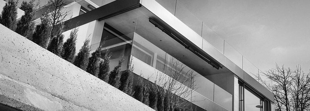 Auskragende Deckenkante mit Glasbrüstung und Sichtbetonmauer