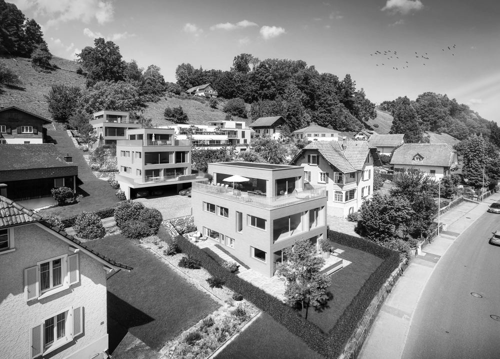 Drei Mehrfamilienhäuser mit heller Holzfassade am Hang, Luftbild
