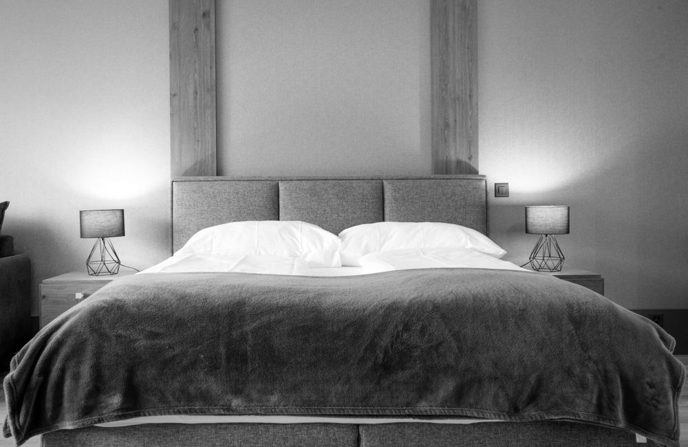 Bett mit gepolstertem Kopfteil zwischen Holzlisenen